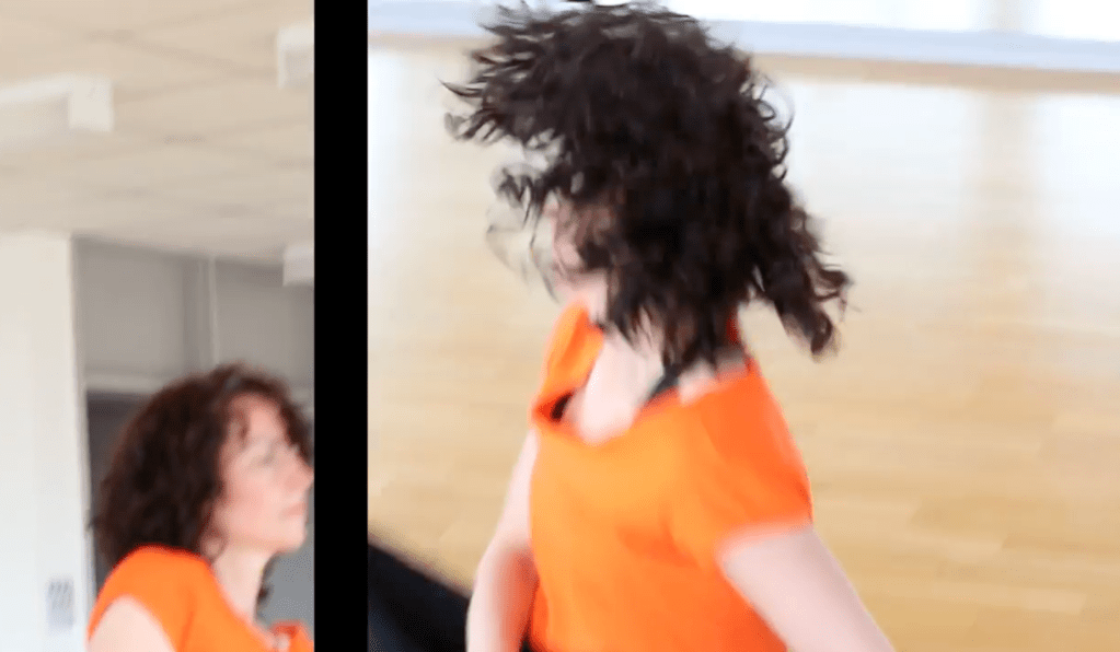 Image showing a frame of the film. It is a split screen. On the right hand side, we see an image of Helen caught mid movement. Her dark curly hair splays out. She wears an orange T-shirt. On the left hand side in a smaller image, we just see a profile of Helen's face. 